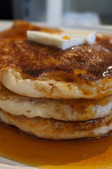 Allergy-friendly cornmeal pancakes topped with vegan butter and maple syrup