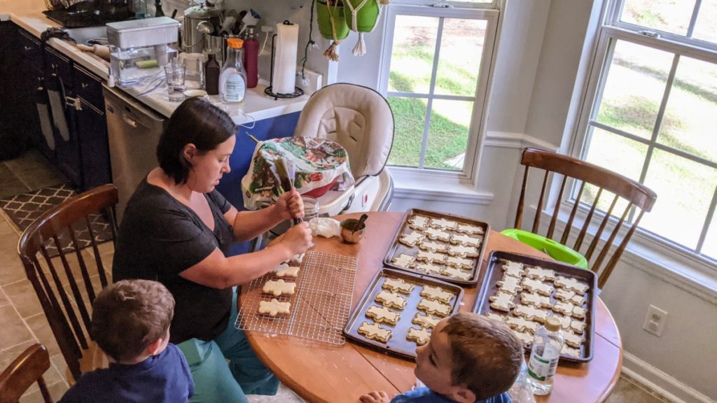 Mother icing sugar cookies while sons watch