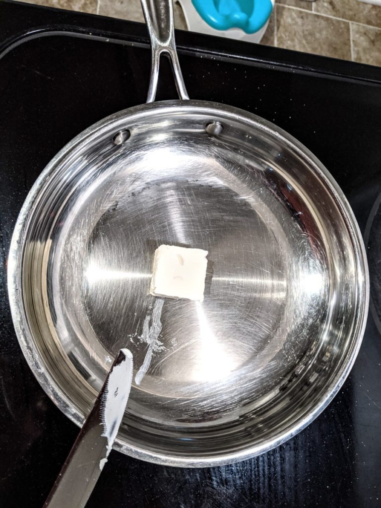 Stainless steel skillet with a tab of Country Crock plant-based butter